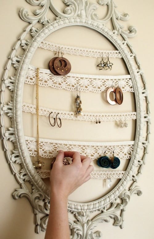 a vintage frame hung on the wall with crocheted lace strips becomes the perfect spot for hanging earrings