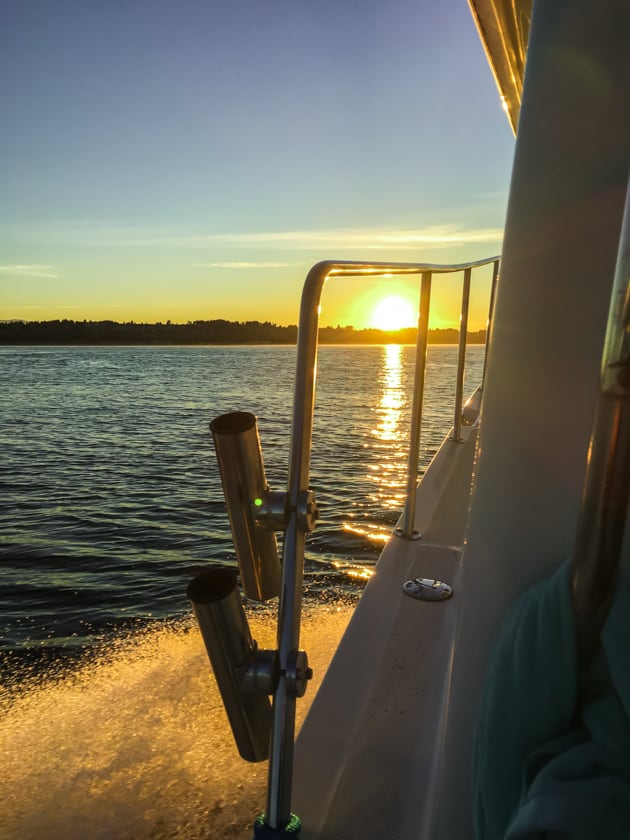 A boat driving into a sunset.