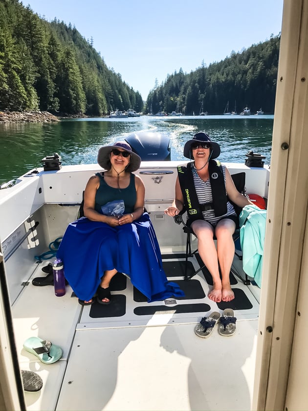 Two women sitting in the back of a boat with bucket hats on.