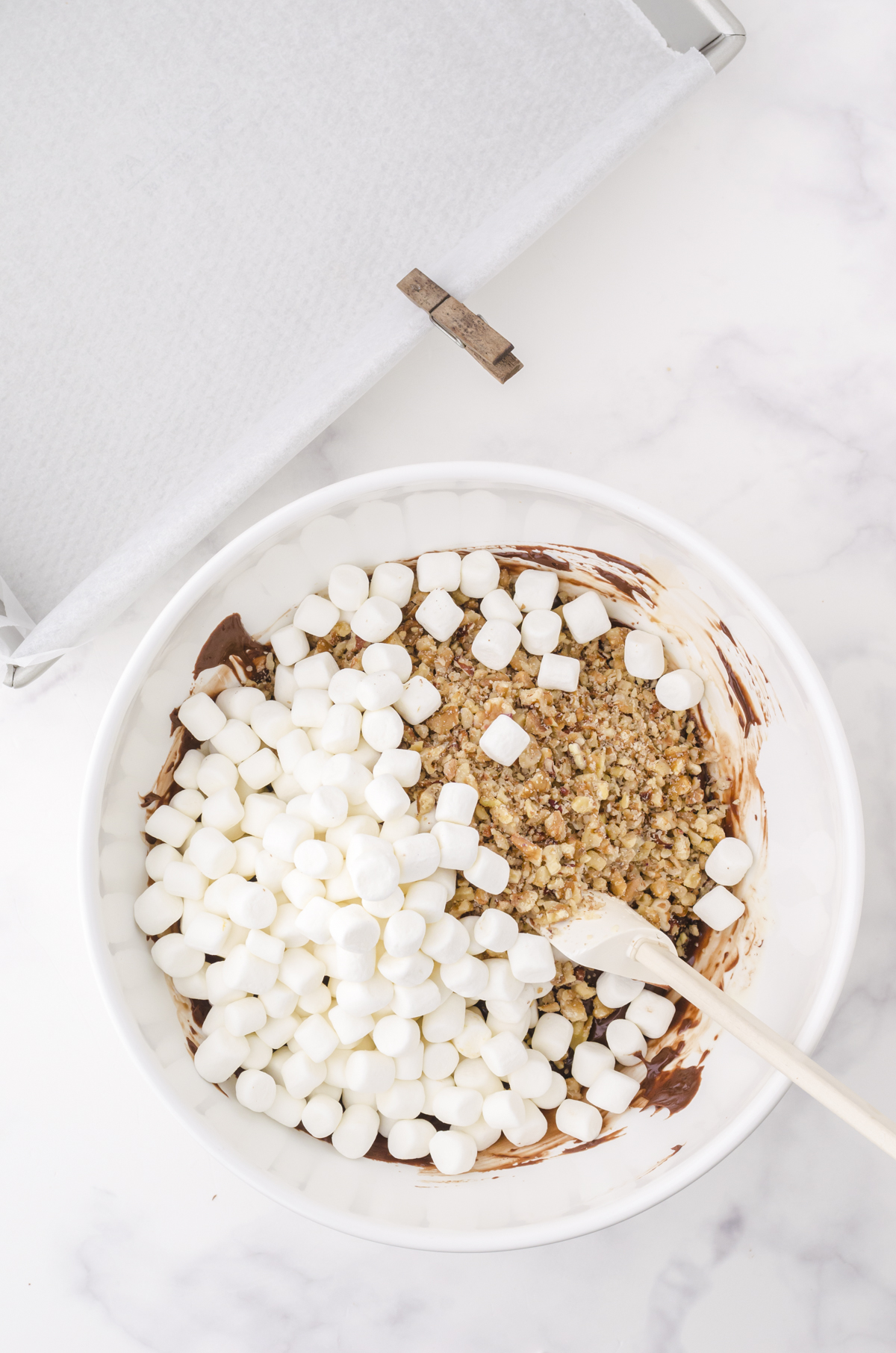Marshmallows and chopped nuts being stirred into microwave fudge.