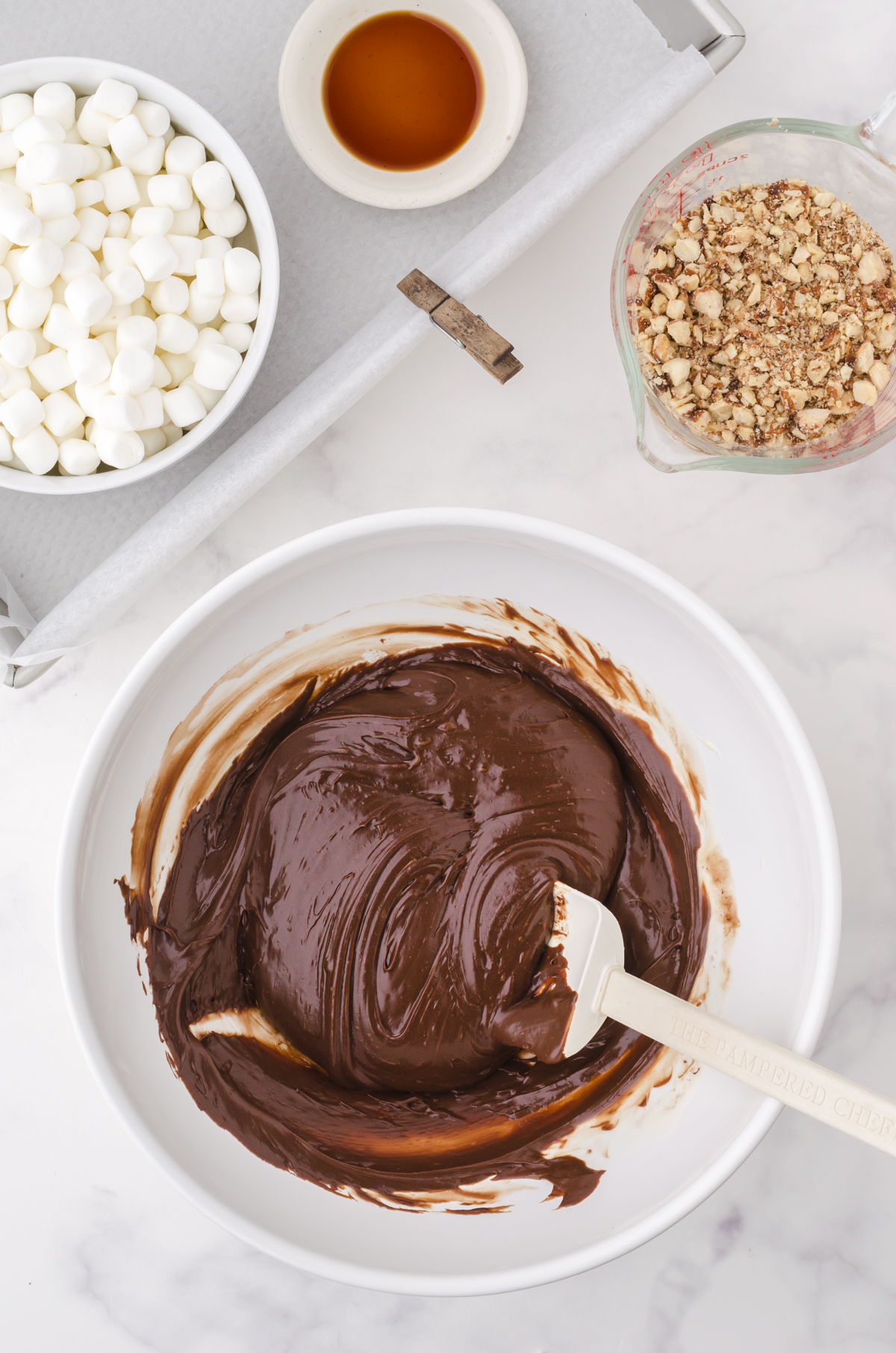 Smooth and glossy microwave fudge being stirred together in a white mixing bowl.