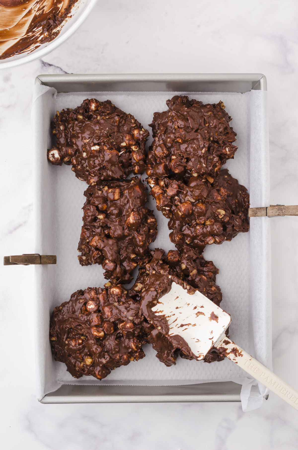 quick chocolate fudge being pressed into a 9 x 13 inch pan with a spatula.