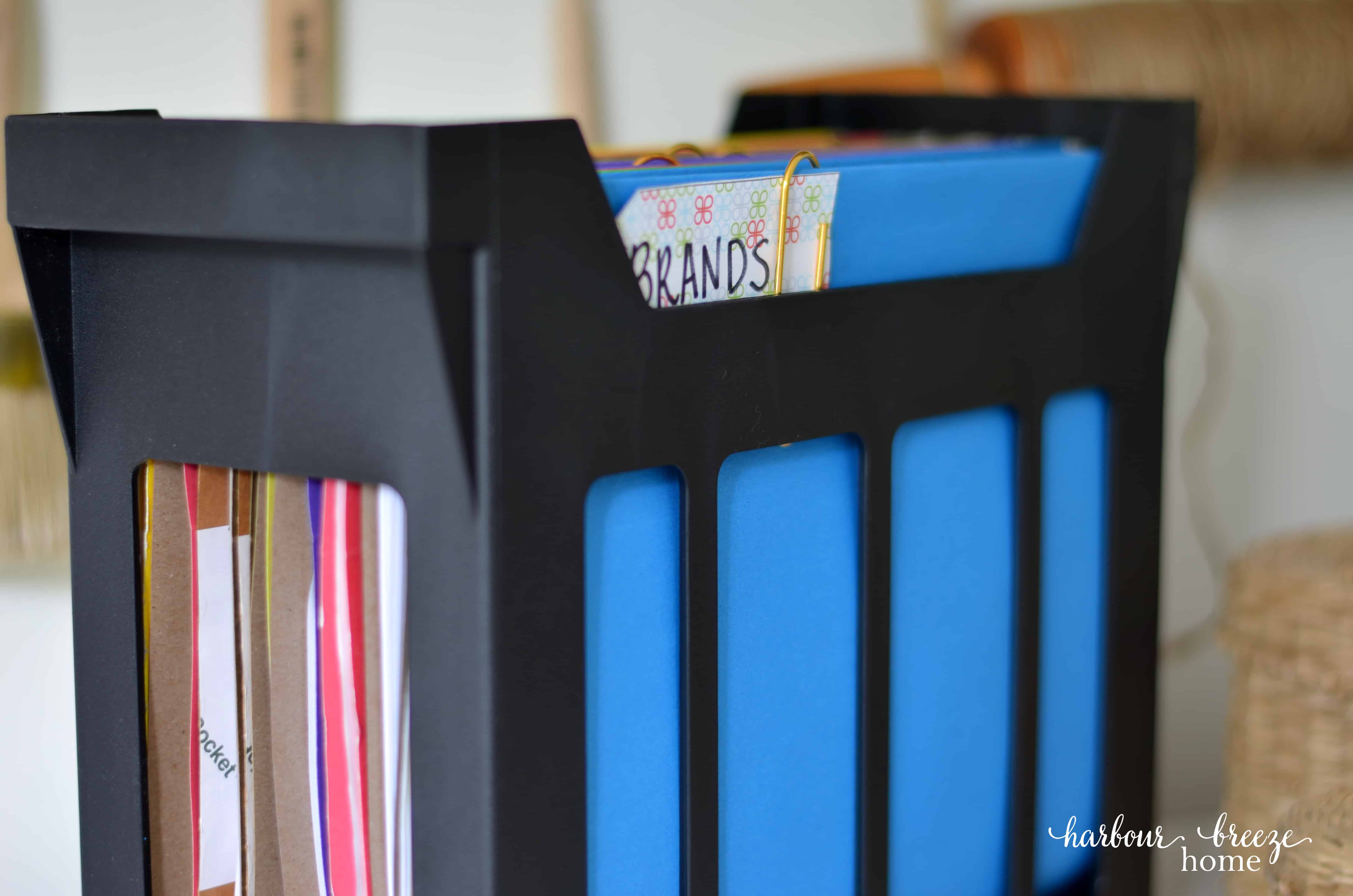 A desktop hanging file folder with bright colored folders in it.