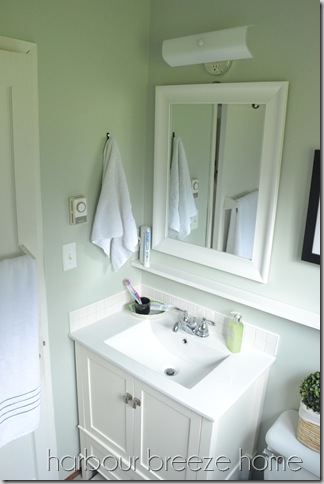 A small bathroom vanity area with a towel hanging on a hook above it.