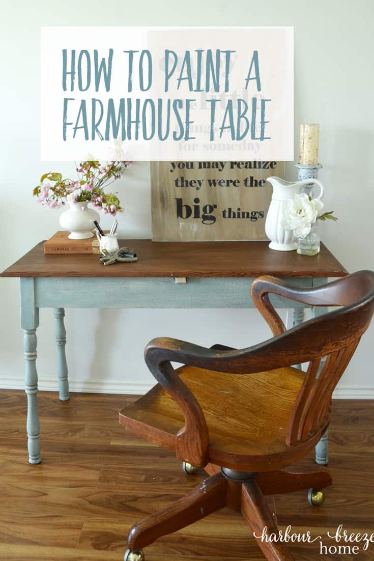 a table with wood stained top and blue legs with an antique oak office chair sitting in front of it and a bouquet of pink flowers on the top