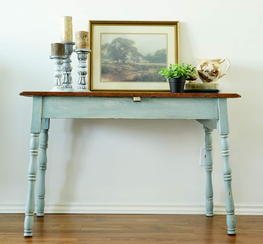 a blue and wood farmhouse table with a green plant and candles on the top