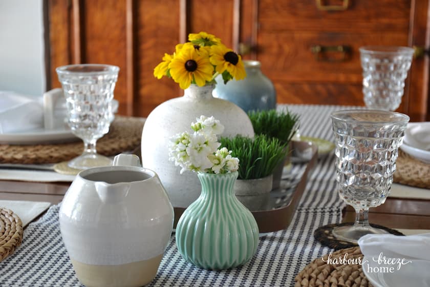 flowers in vases scattered down the center of the table