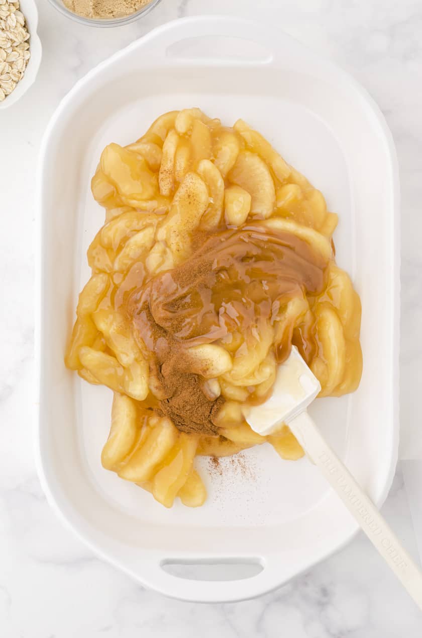apple pie filling and cinnamon being stirred together as the base for apple crisp with pie filling