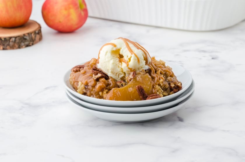 apple crisp with apple pie filling on a plate with ice cream and caramel drizzle