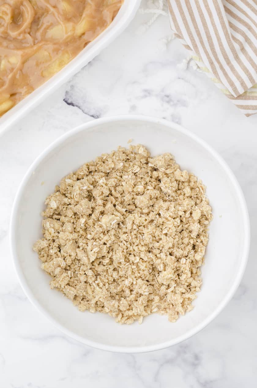 Crumb topping for apple crisp with pie filling in a bowl.