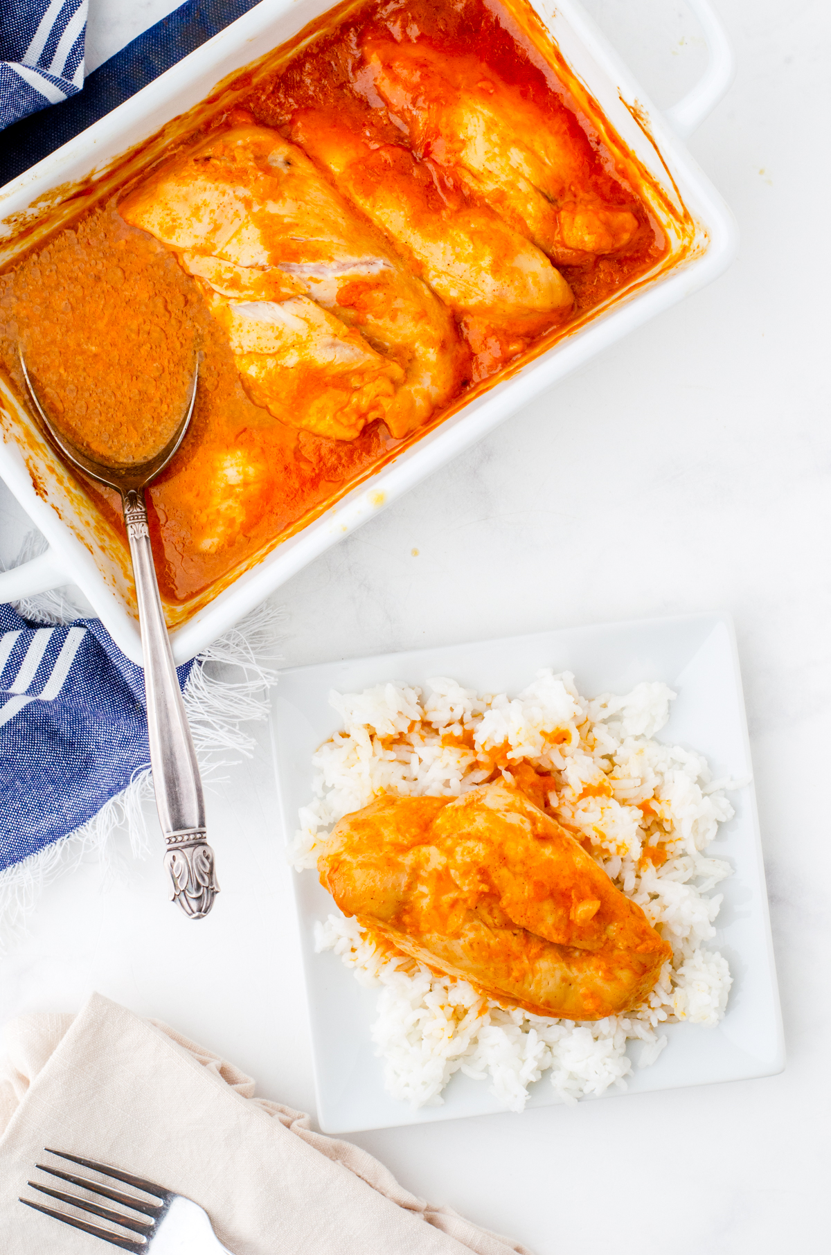 A pan of apricot chicken breasts with a serving on a bed of rice beside it.