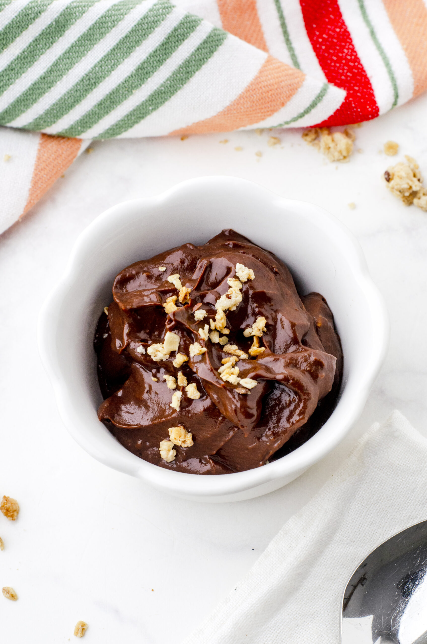 bowl of chocolate avocado pudding with a spoon beside it