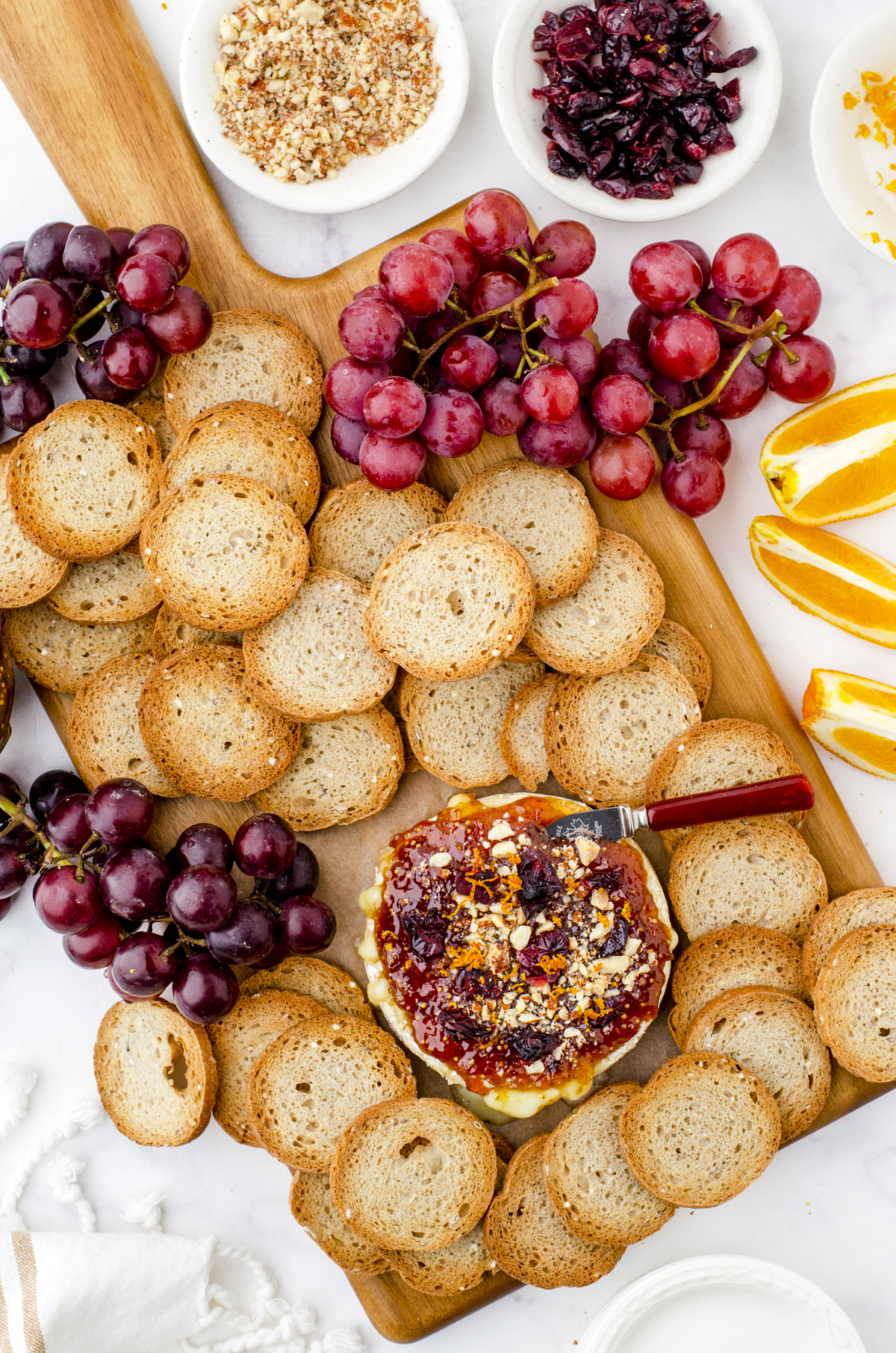 baked brie on a charcuterie tray with crackers and fruit