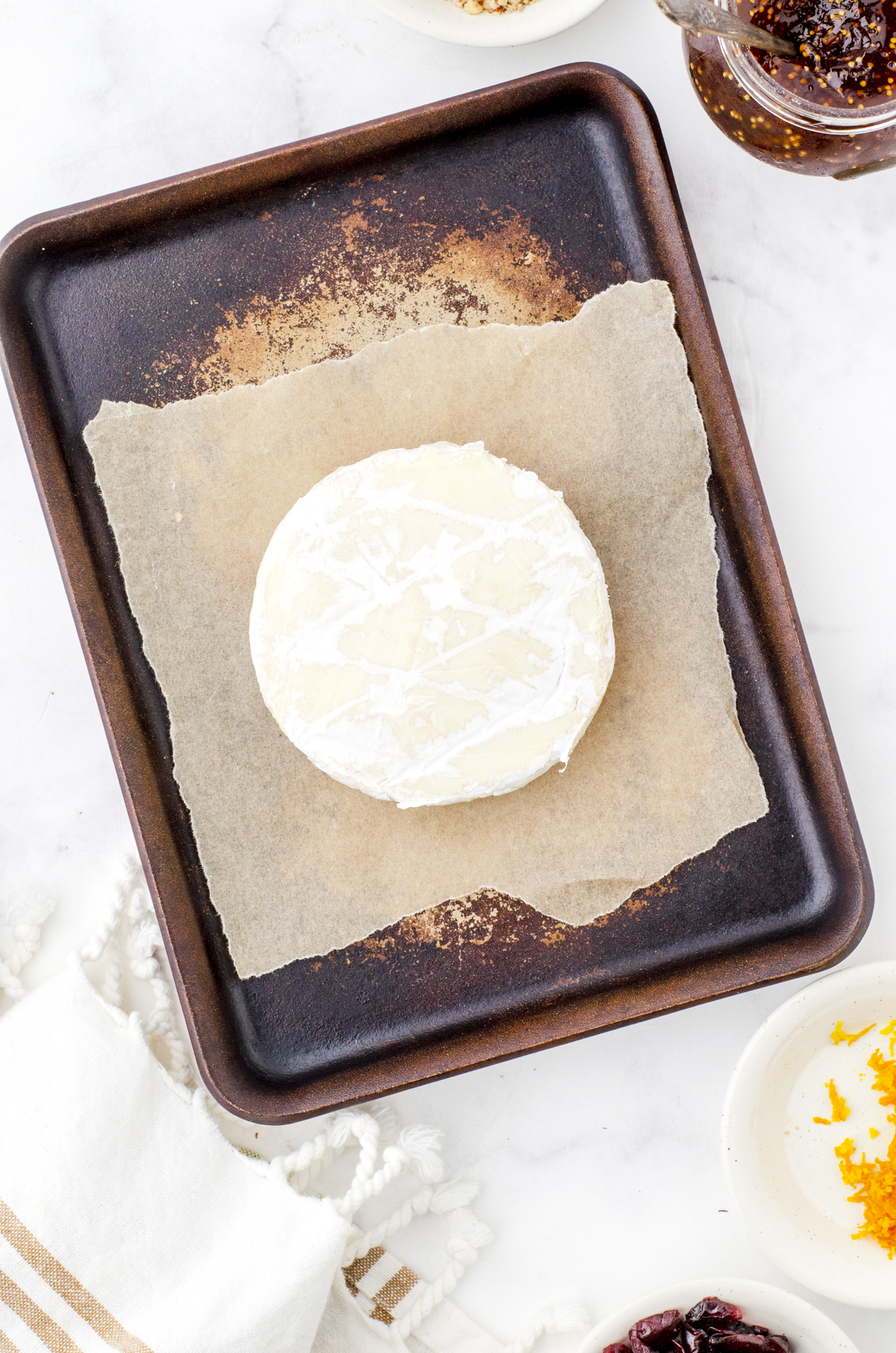 round of brie on a parchment lined baking sheet