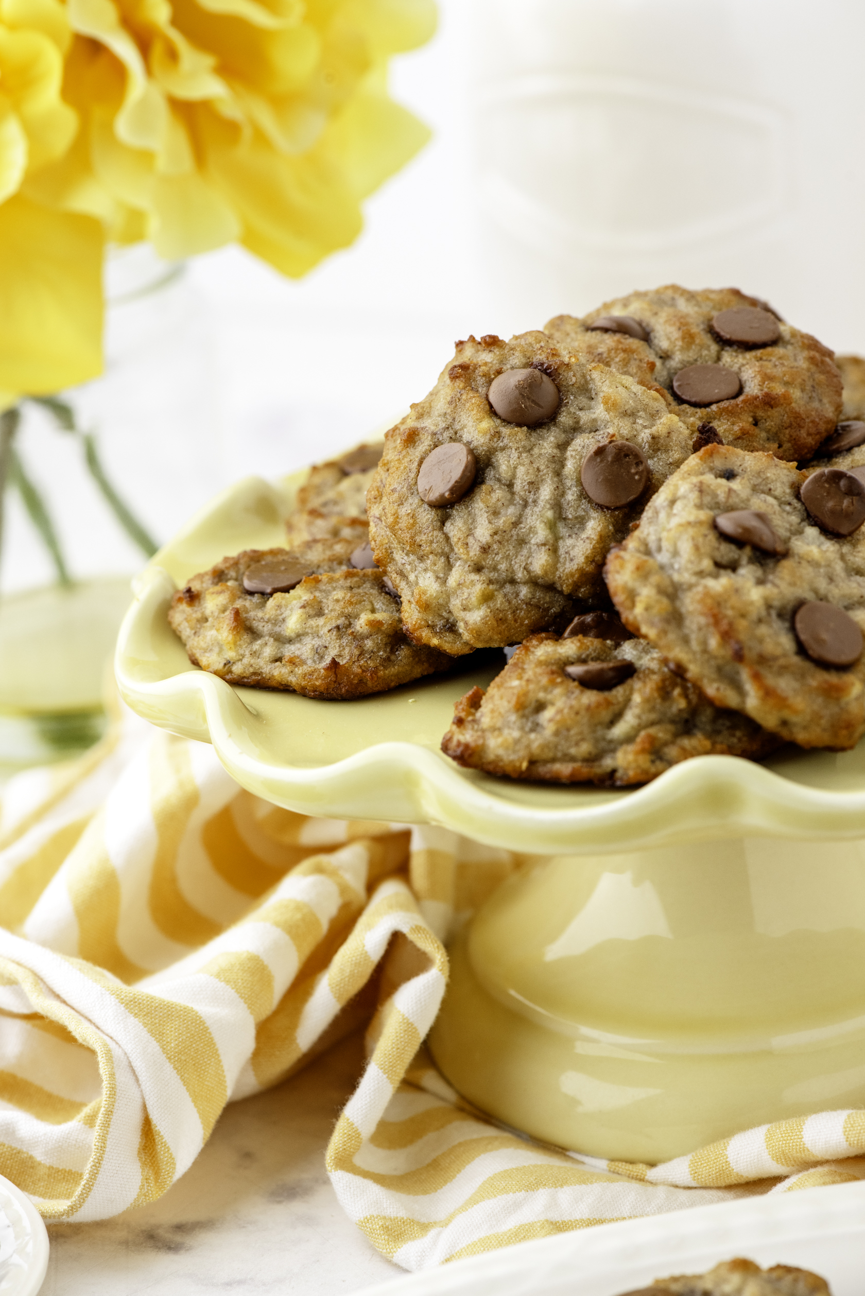A yellow cake platter with a pile of 2-bite banana bread cookies on it.