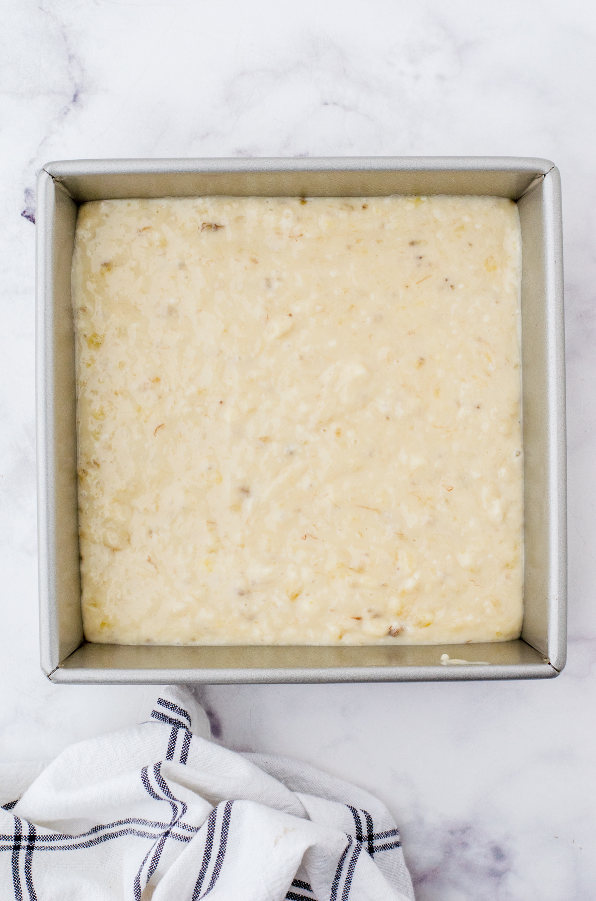 Banana cake batter poured into an 8x8 inch pan.