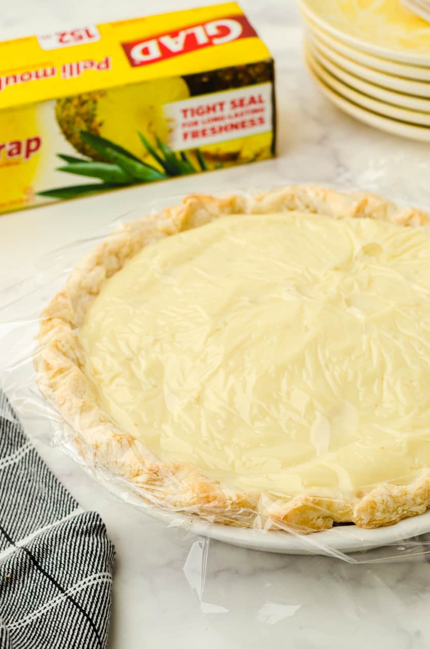 Banana Cream pie with pudding with plastic wrap covering it.