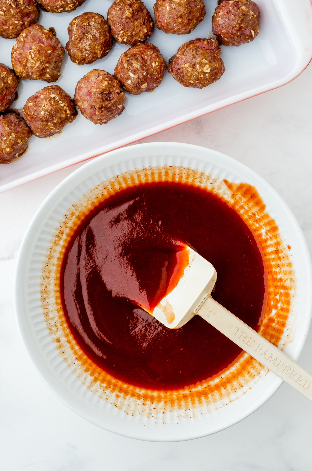 homemade barbecue sauce for meatballs stirred in a bow.