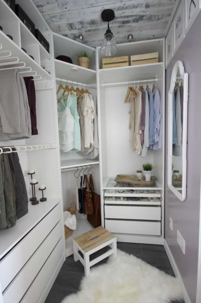 Small closet organization with a wood slat ceiling, hanging rods for hanging clothes, storage shelves above with crates, and pull out drawers below.
