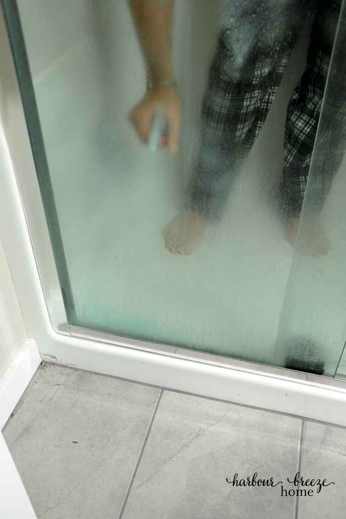 A man spraying on homemade shower door cleaner in a shower
