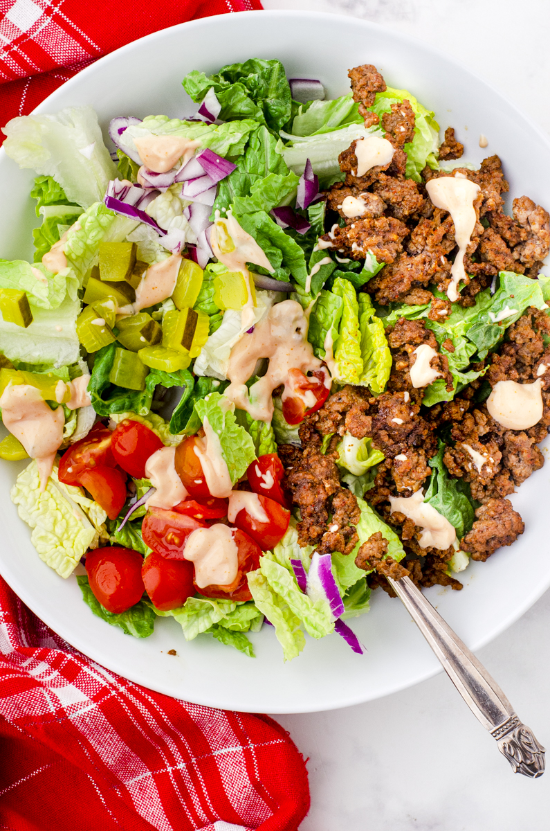 a heathy big mac salad bowl ready to eat in a big white bowl.
