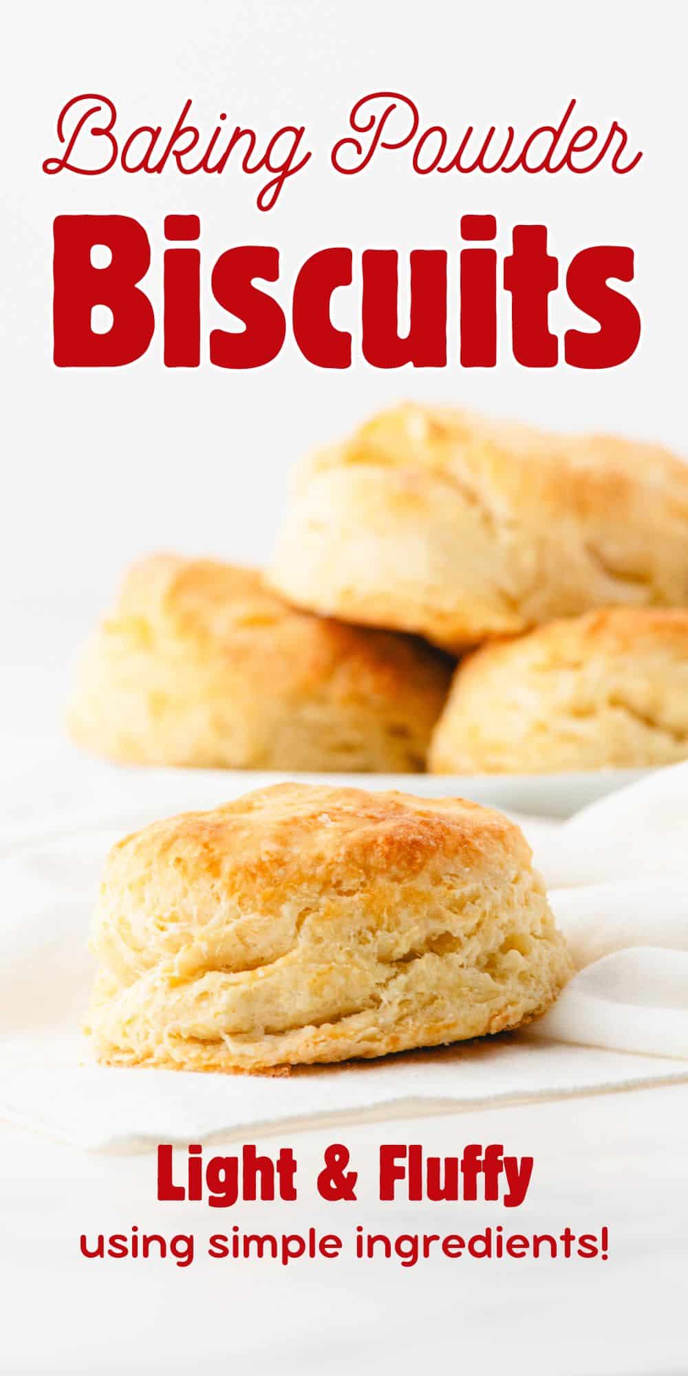 A baking powder biscuit sitting on a napkin with a plate of biscuits behind it.