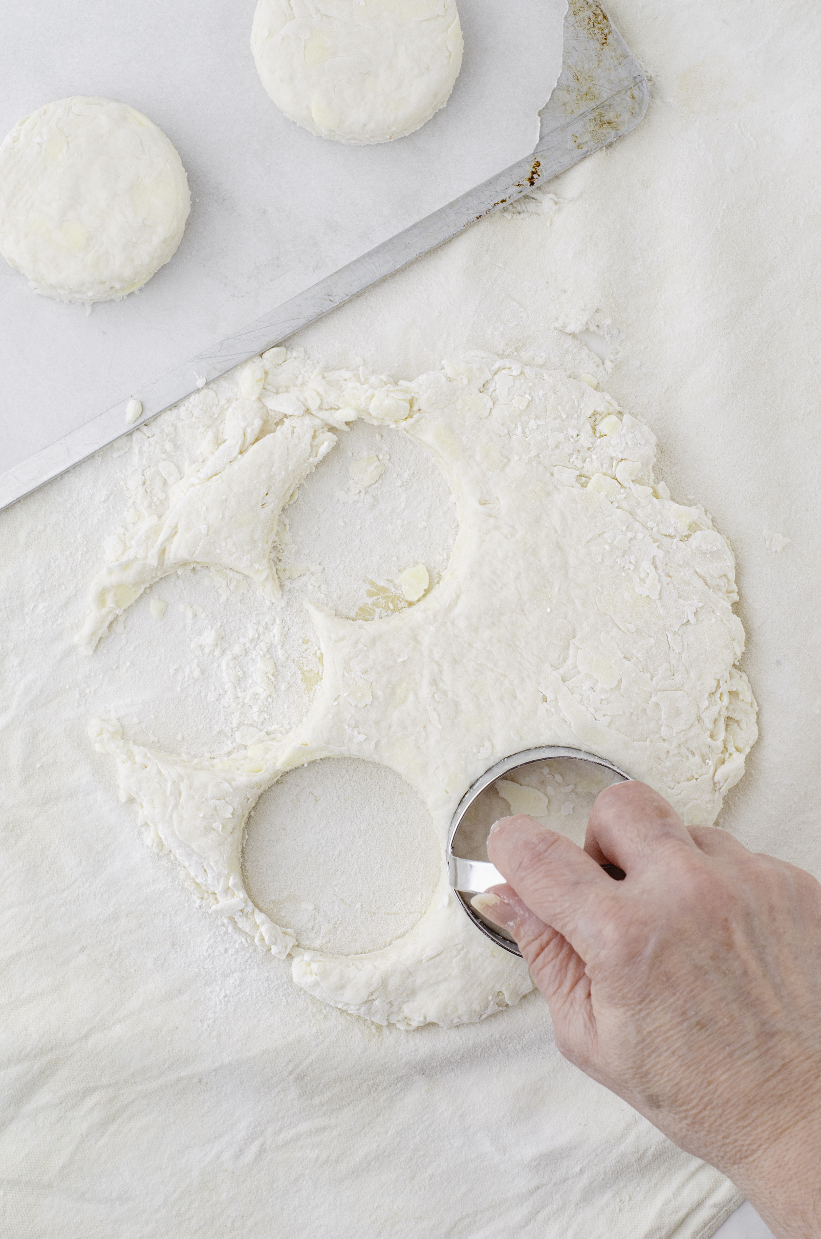 a women using a biscuit cutter to cut biscuits out of dough