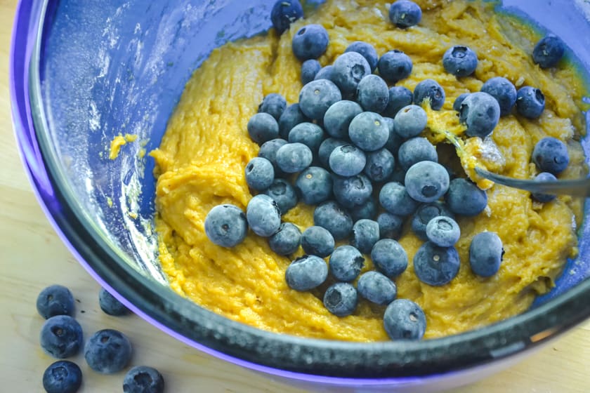 Blueberries being stirred into pumpkin muffins batter