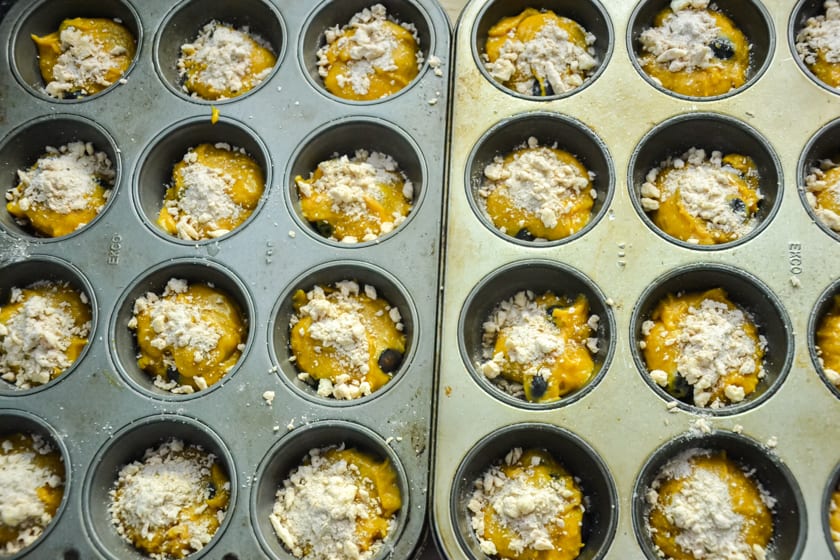 Pumpkin muffins batter in muffin tins with streusal topping on the top.