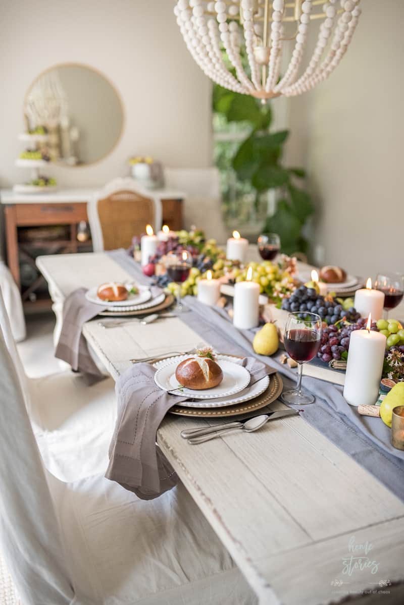 a Fall table setting with a blue table runner and a variety of grapes and candles as the centerpiece