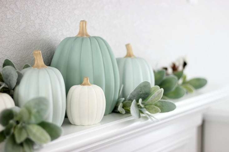 blue green painted pumpkins on a fireplace mantel