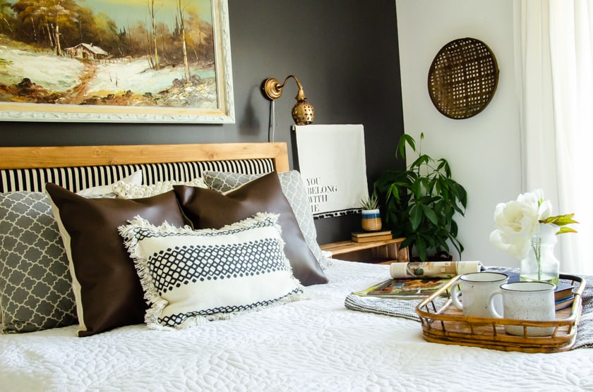 The bed in a boho style bedroom with a tray with flowers and coffee cups on it.
