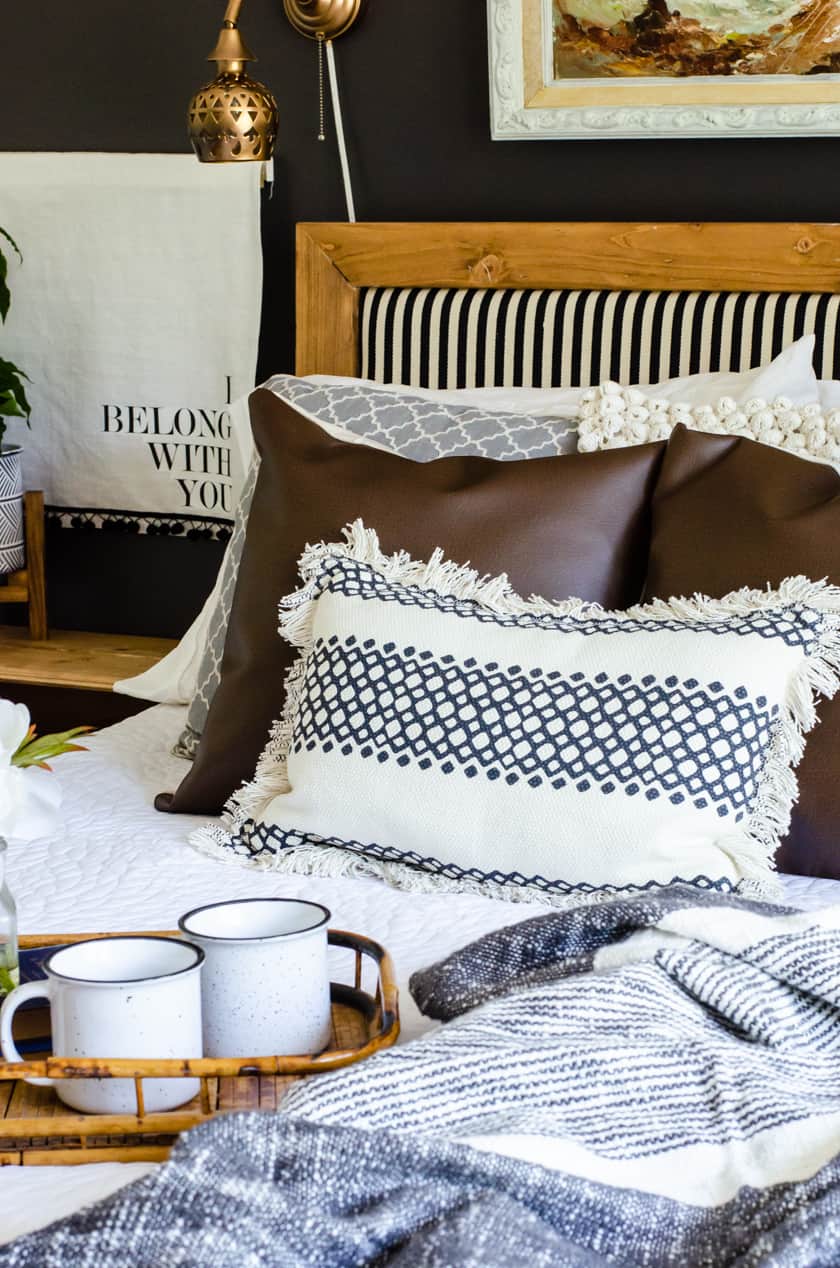The mixture of textures on throw pillows on a boho style bed including leather, crocheted, woven, and patterned.
