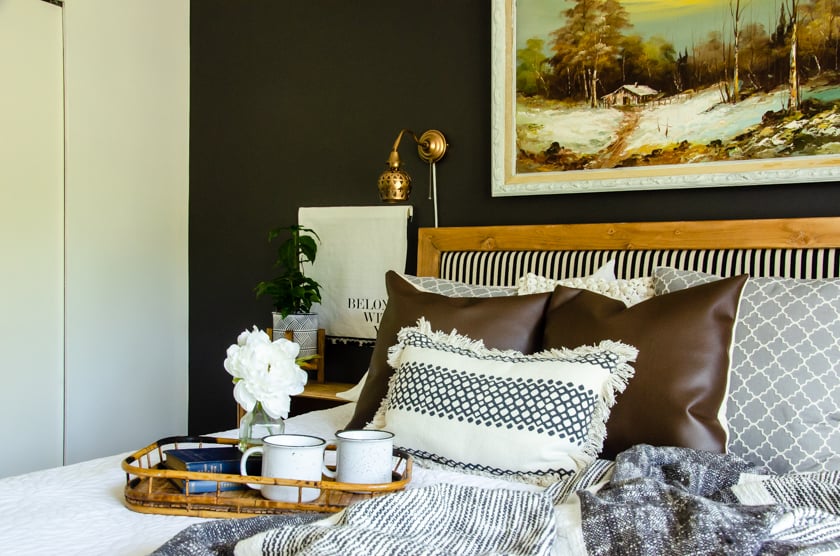 A boho style bedroom featuring a mixture of woods, whites, leather brown, and gray.