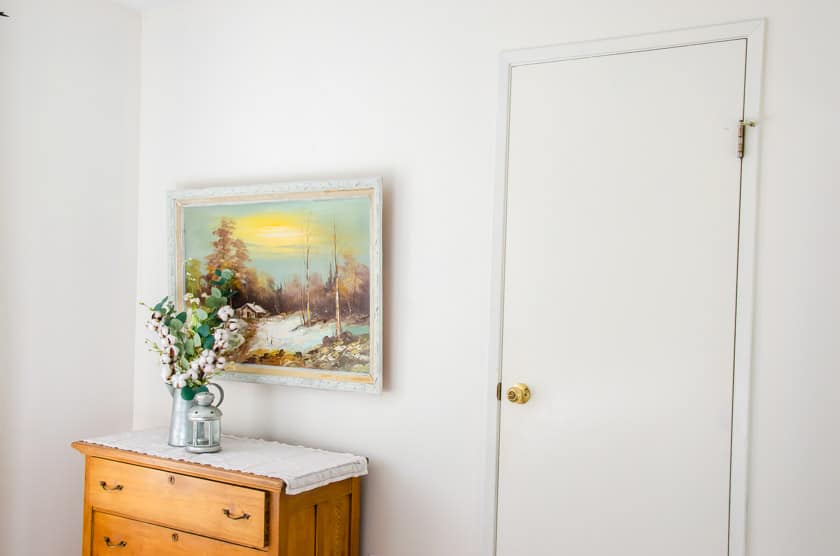 A white wall with picture above the dresser.
