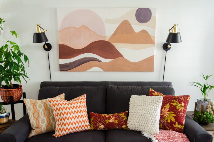 Gray Lazboy couch with boho style landscape art above it.