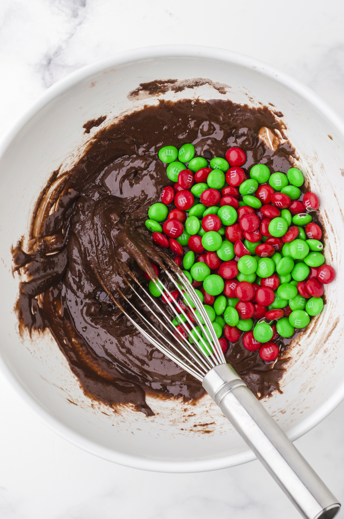 Brownie mix cookie ingredients being stirred together in a large mixing bowl.