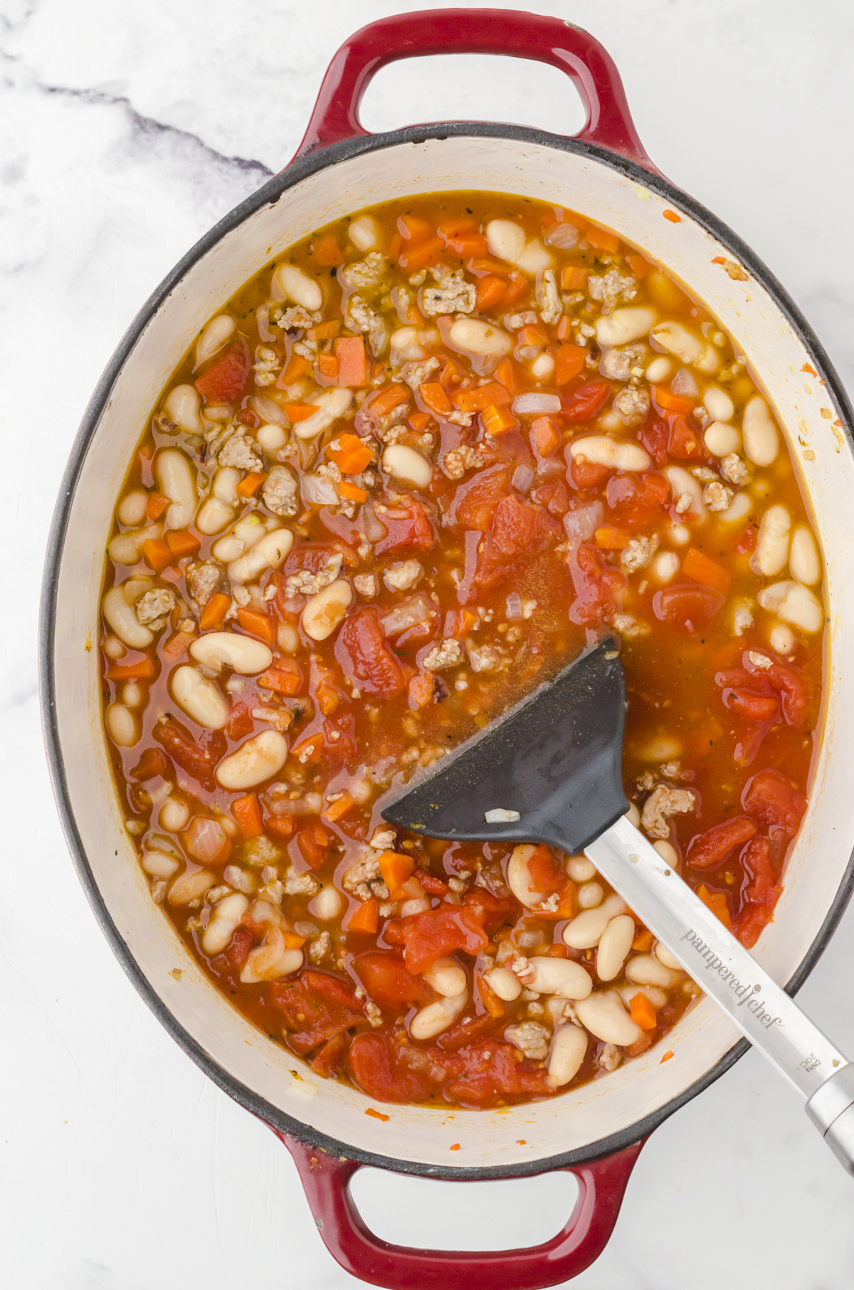 All ingredients for Rachael Ray Buffalo Chicken Chili in a dutch oven being stirred together with a large spoon.