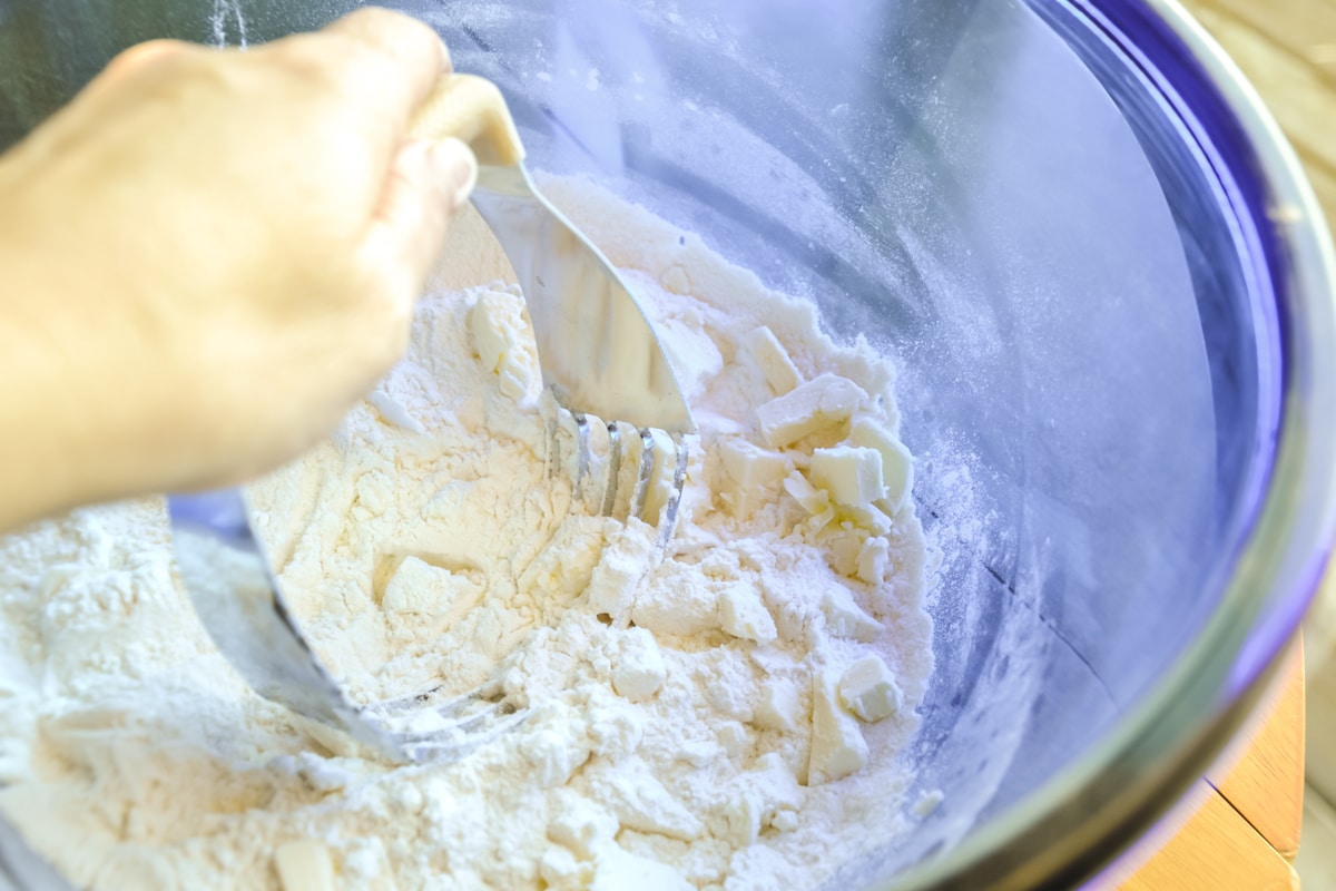 Butter being cut into the dry ingredients for this buttermilk cranberry scone recipe.
