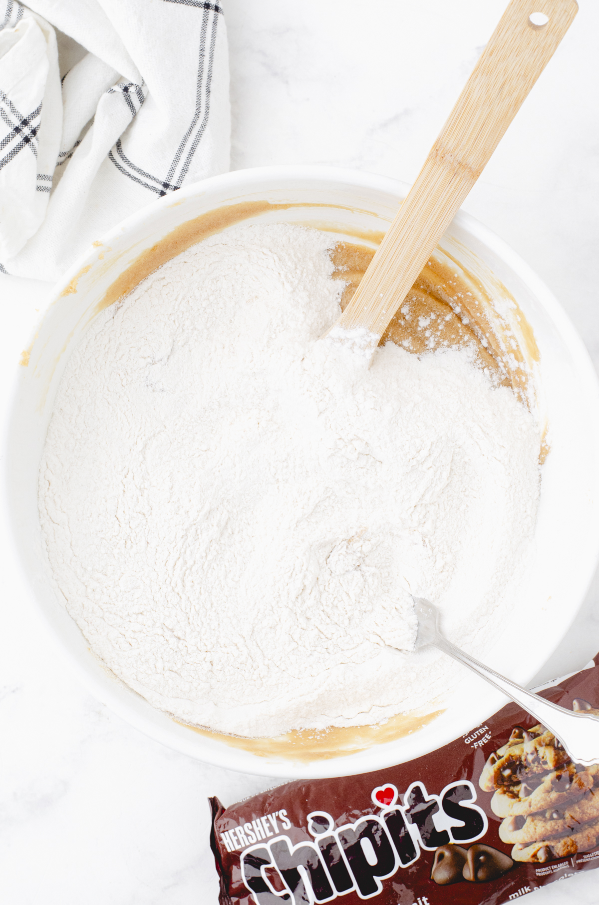 A fork in the dry ingredients after it has mixed them together on top of the smooth butterscotch brownie batter below it.