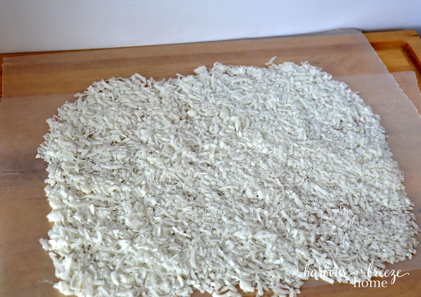 Coconut sprinkled onto waxed paper in preparation for church window cookies dough to be placed on it.