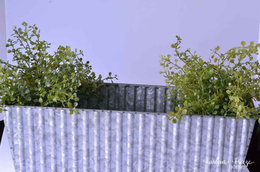 Start filling the centerpiece flower boxes by putting the wispy faux greenery on each end.