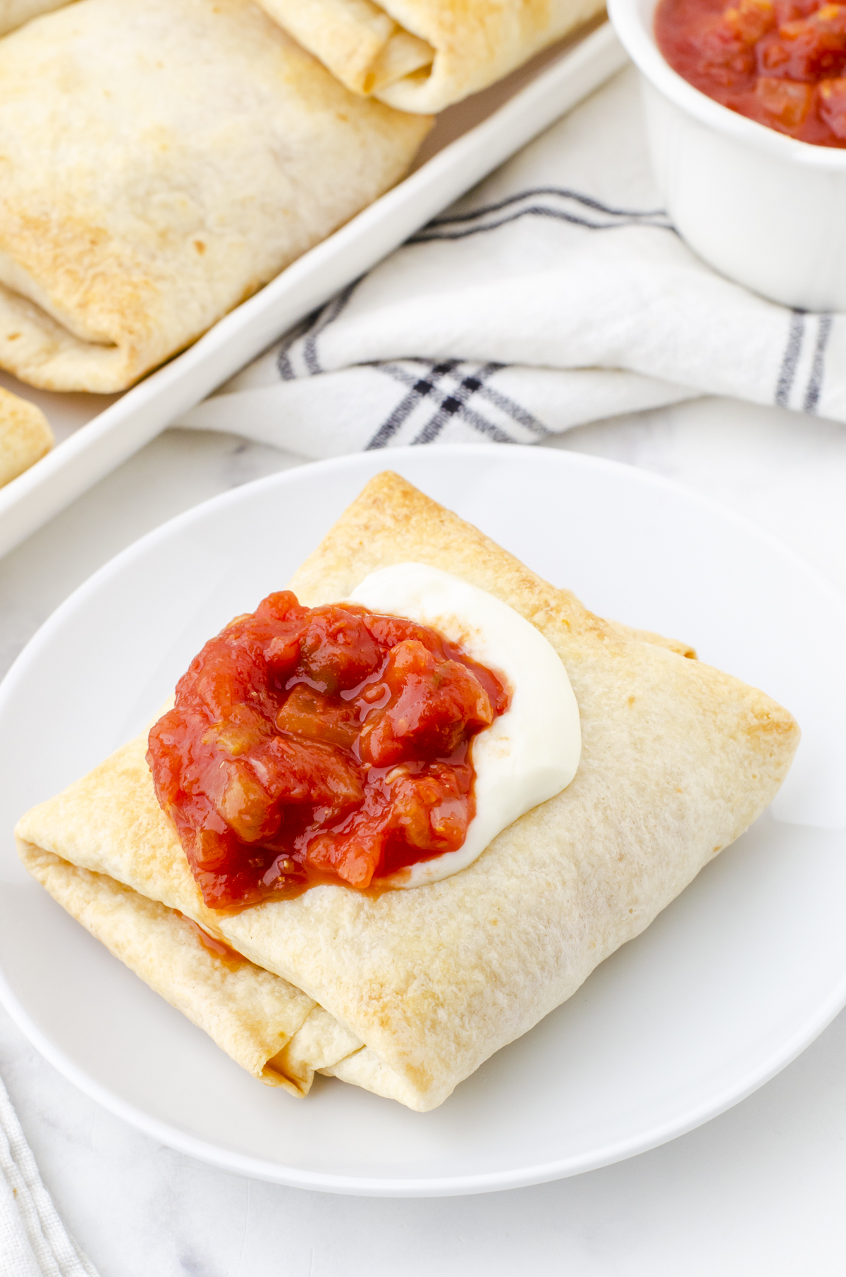 Chicken chimichanga on a plate with salsa and sour cream