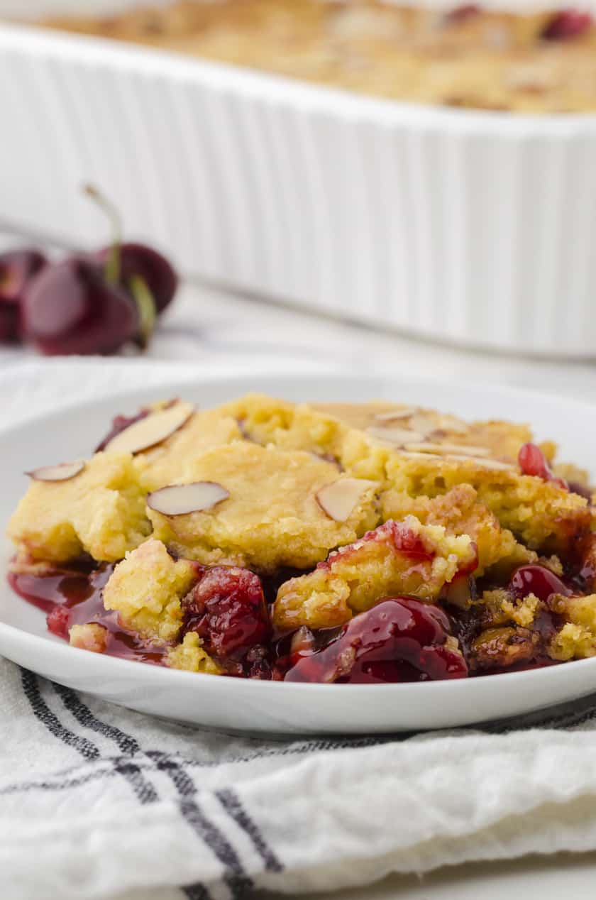a piece of dump cake with cherries on a dessert plate.