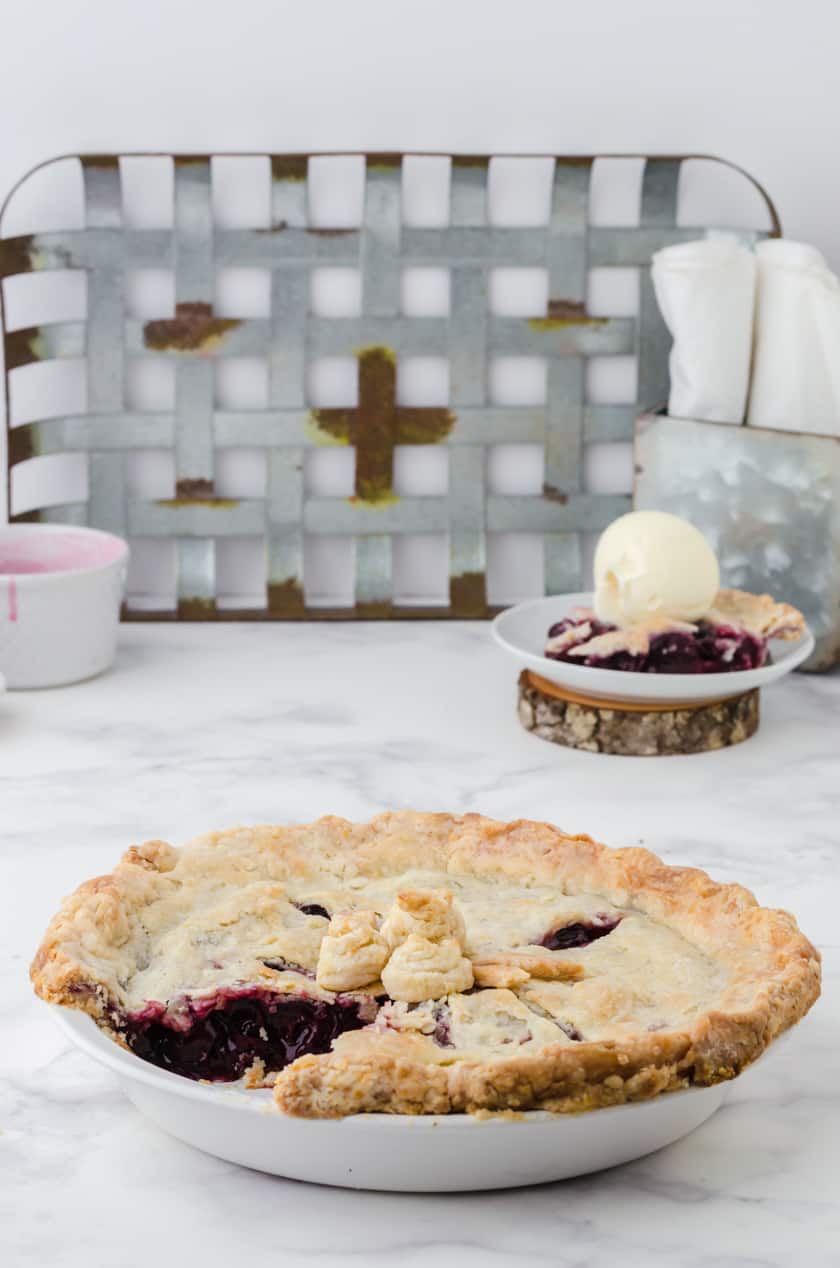 Whole cherry pie with slice out of it.