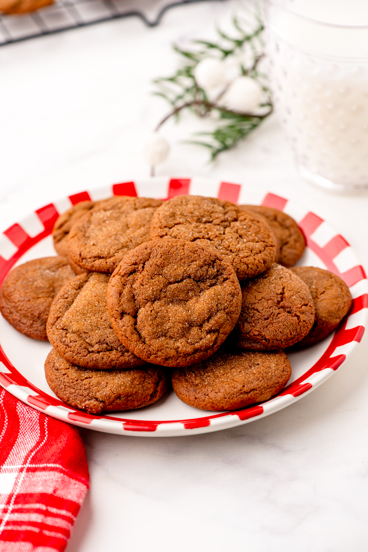 A plate of soft and chewy gingersnaps with a glass of milk beside it.