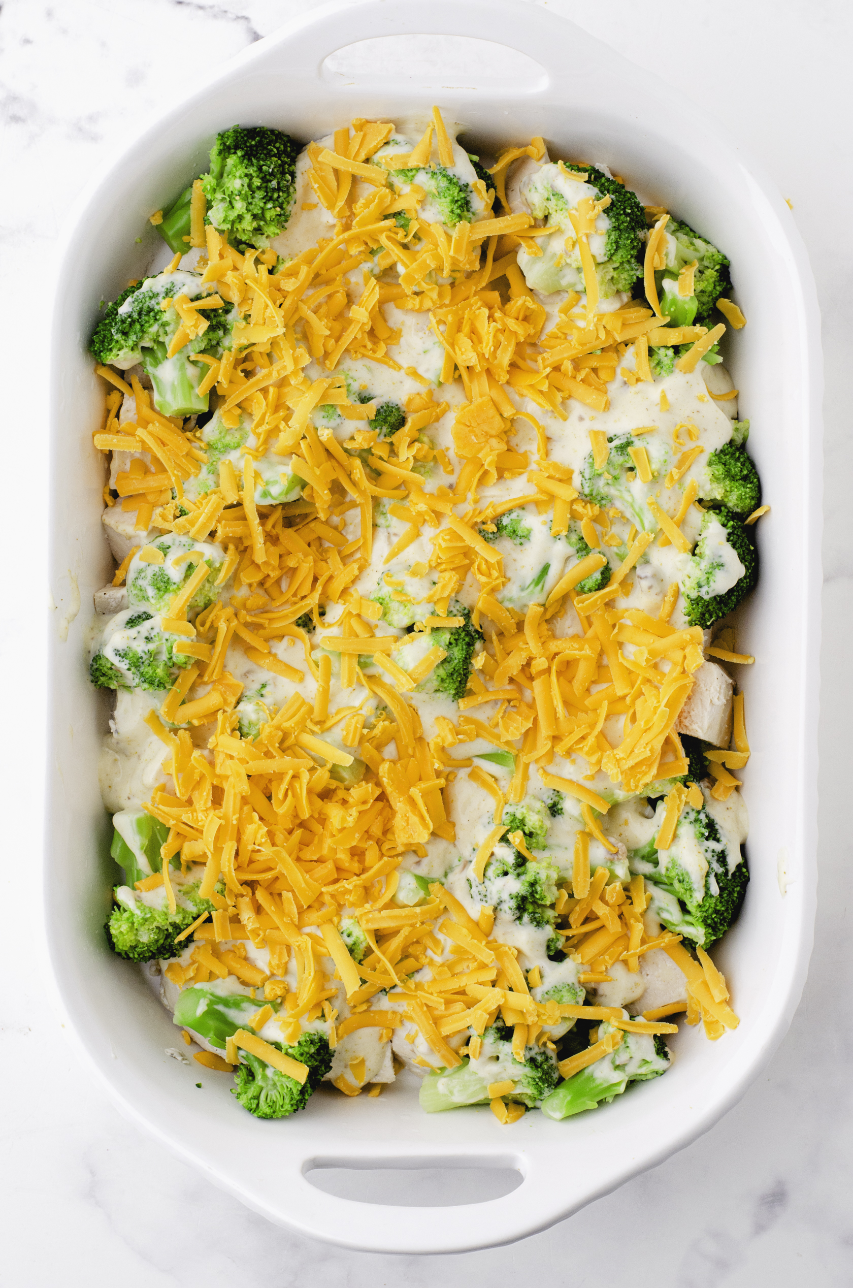 Grated cheddar cheese on top of chicken divan casserole