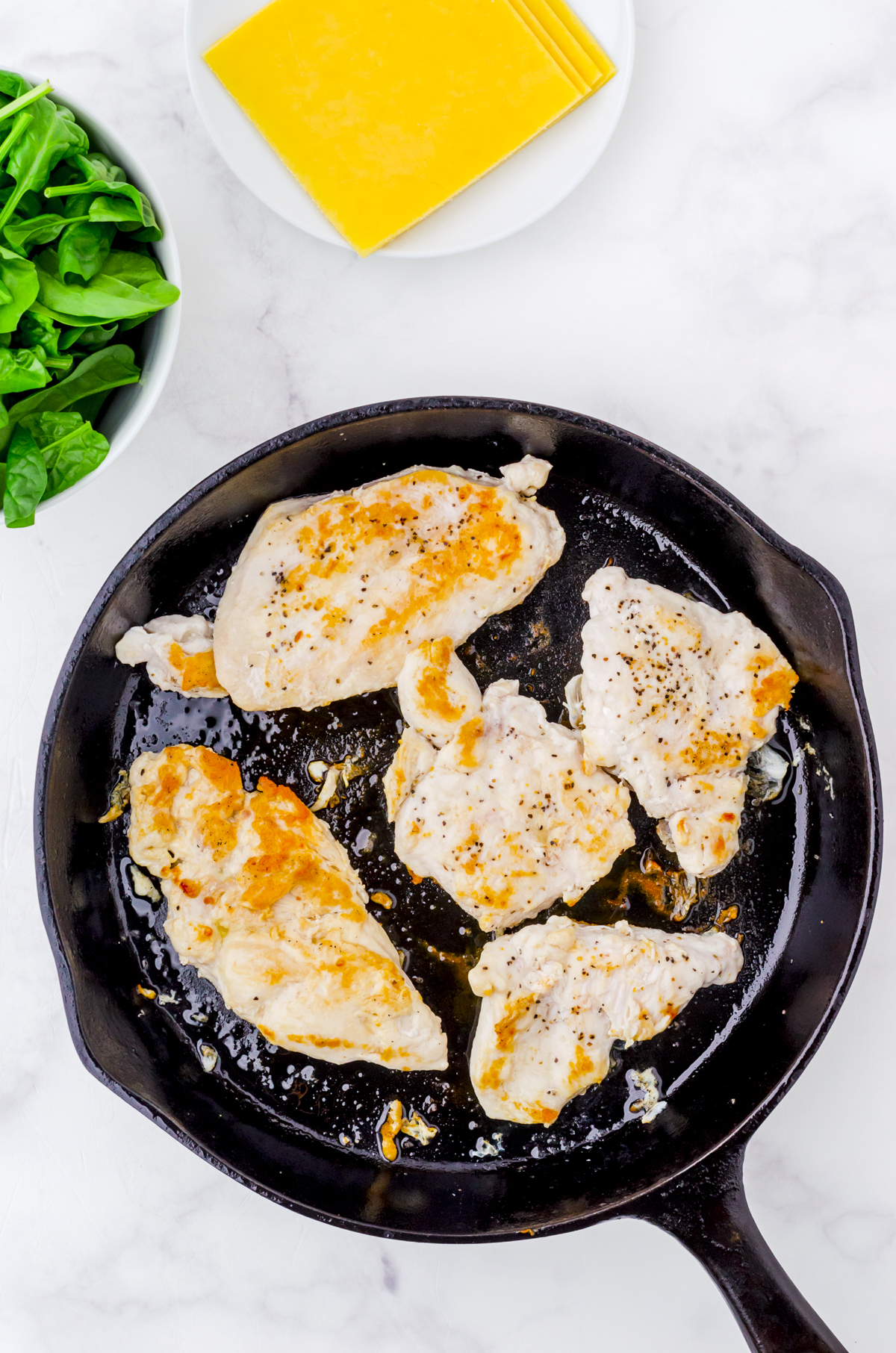 Chicken breasts browning in a cast iron pan.