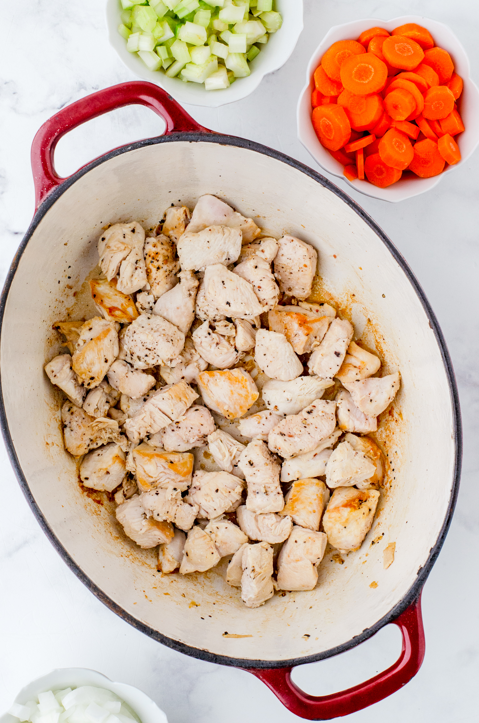 a dutch oven with cooked chicken pieces in it for chicken noodle soup.
