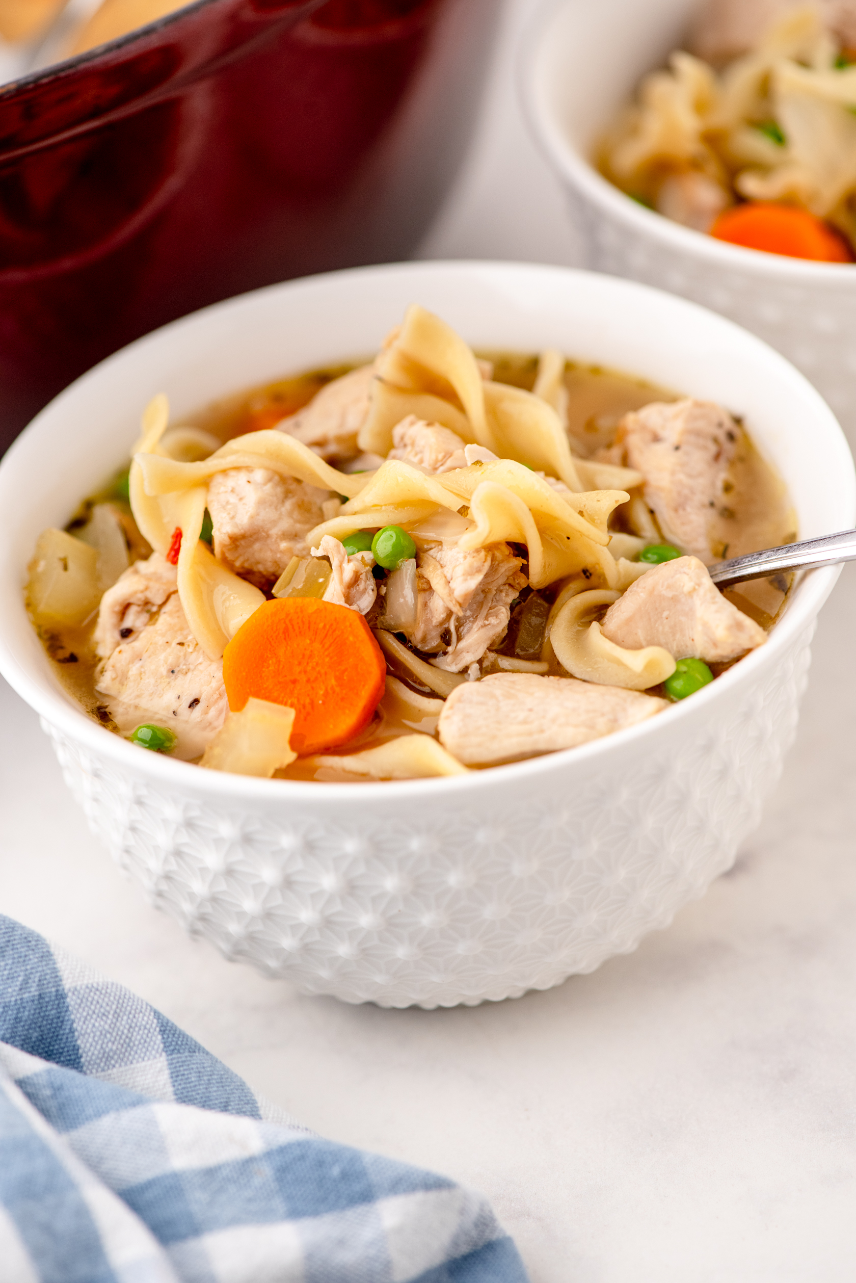 A bowl of chicken noodle soup with a spoon in it.